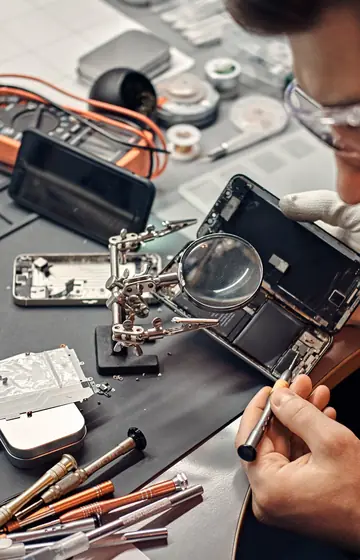 Smartphone-Werkstatt, geöffnetes Handy unter der Lupe mit Pinzette