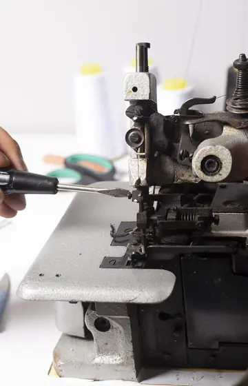Nähmaschinenwerkstatt, Schraubendreher an der Industrienähmaschine, Garnrollen im Hintergrund